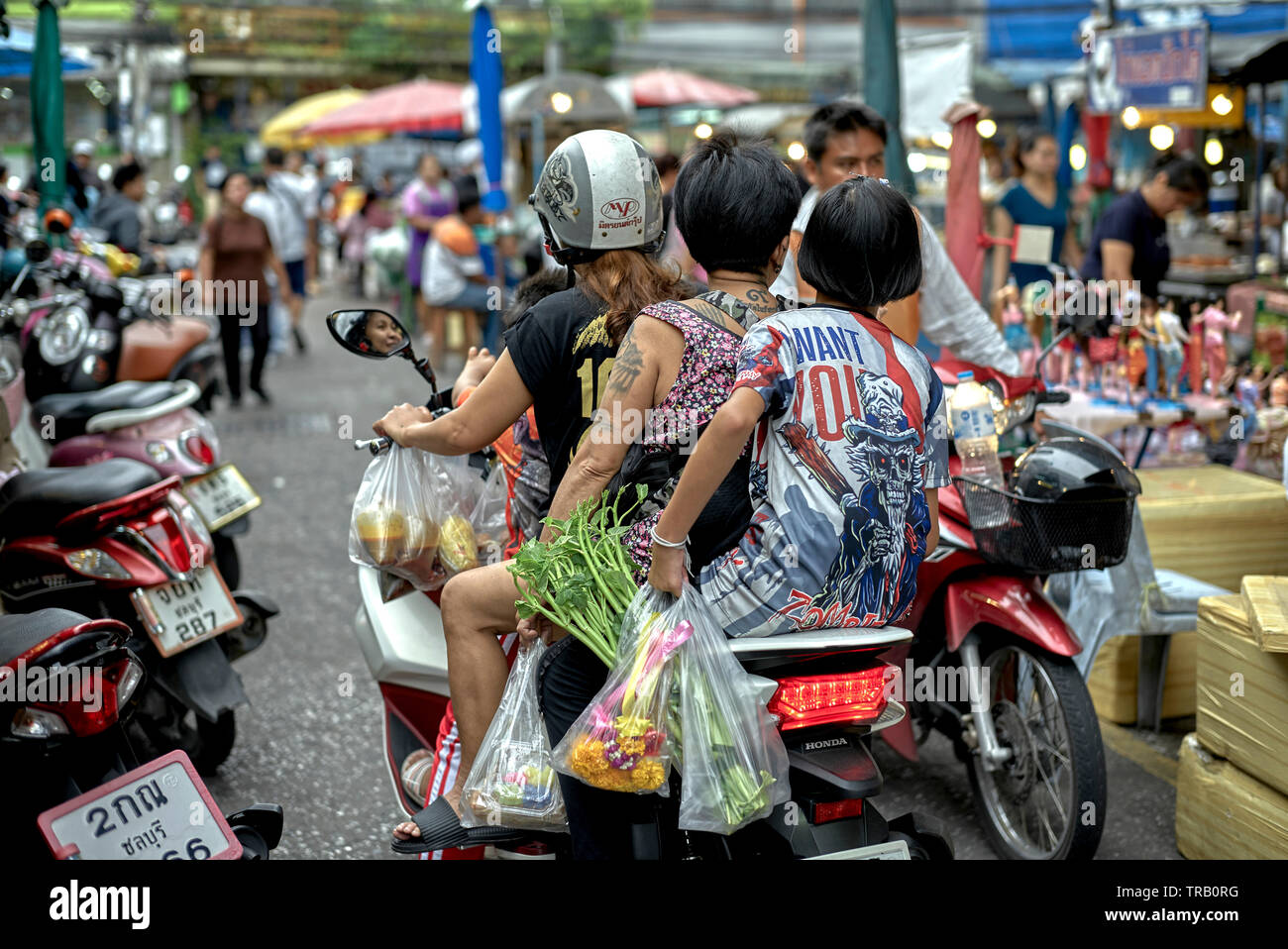 Thailandia famiglia moto. Shopping di cibo con tre generazioni di donne che guidano una moto attraverso un mercato di strada Foto Stock