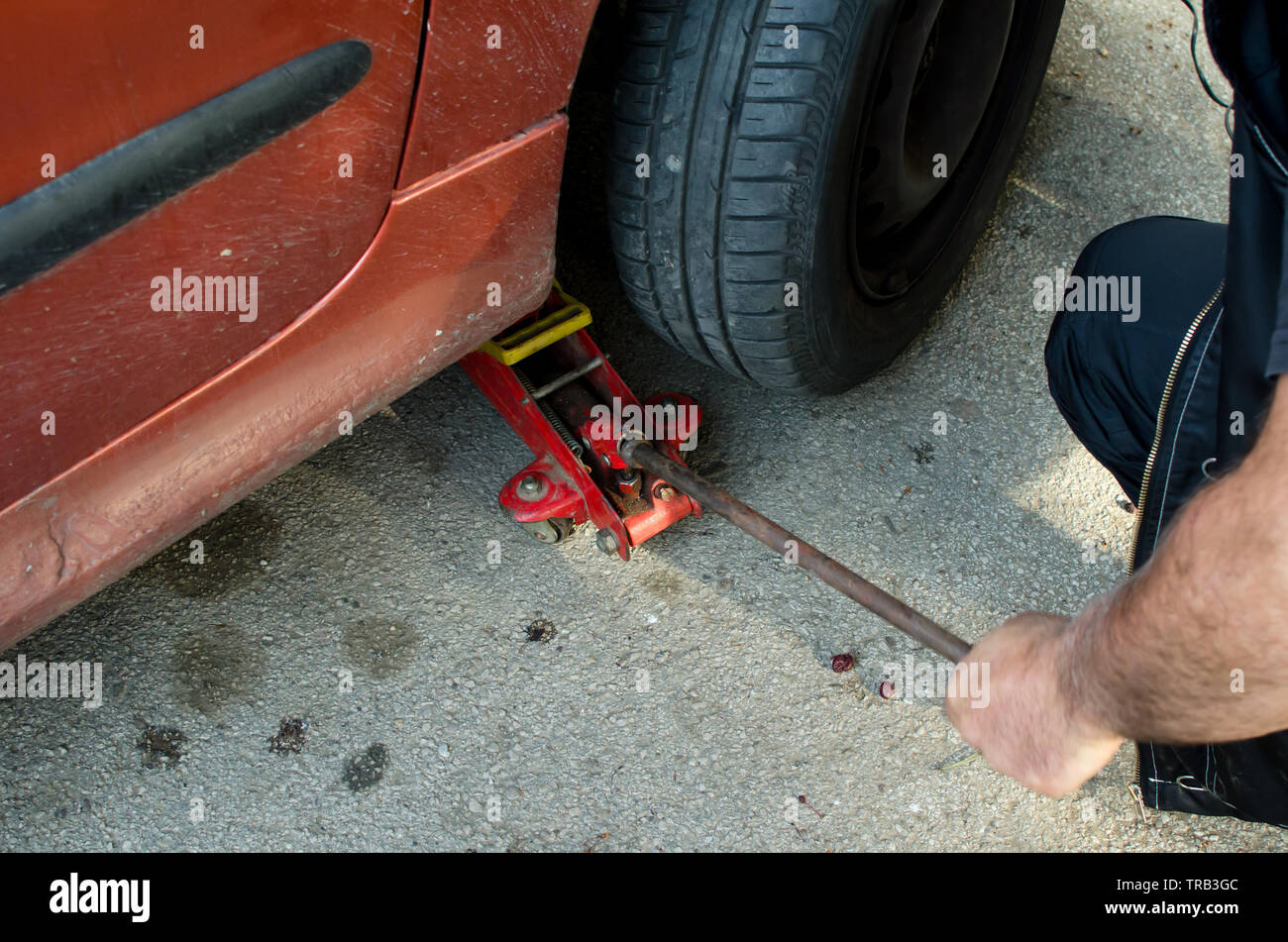 Meccanico automatico preleva un cric per cambiare un pneumatico su strada,close up Foto Stock