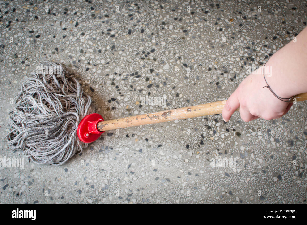 Donna mano azienda di pulizia sporchi mop con il bastone di legno grigio  pulizia superficie punteggiata Foto stock - Alamy