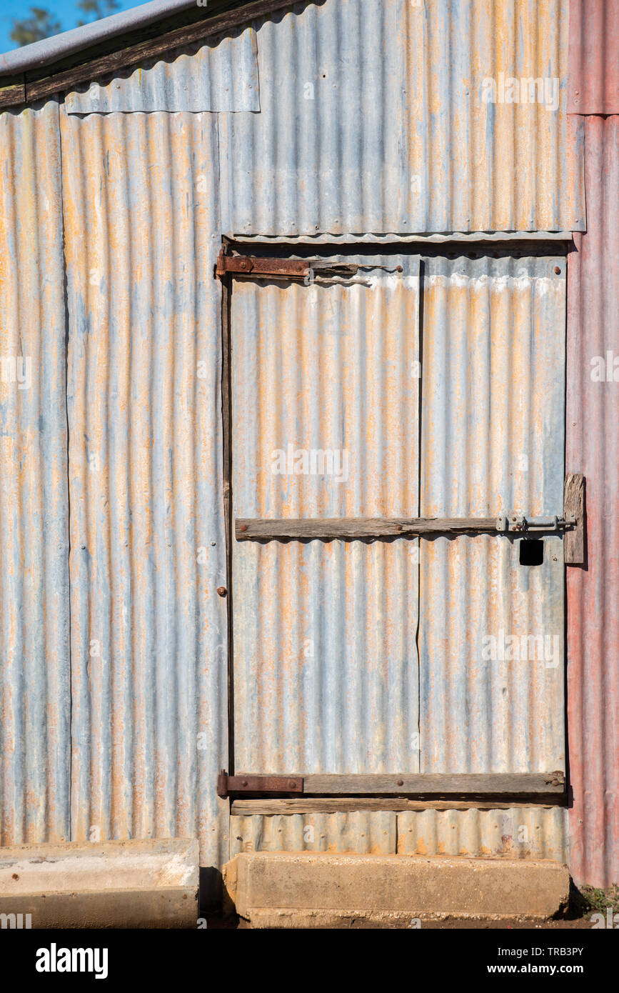 Un bloccato porta a battente e la vista laterale di un vecchio ferro zincato capannone o un fienile in una fattoria nel nord-ovest del Nuovo Galles del Sud, Australia Foto Stock