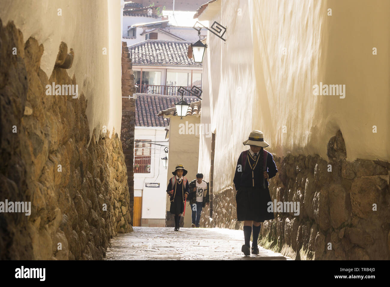 Cusco scena di strada - scolari in uniforme andare a scuola a piedi al mattino. Foto Stock