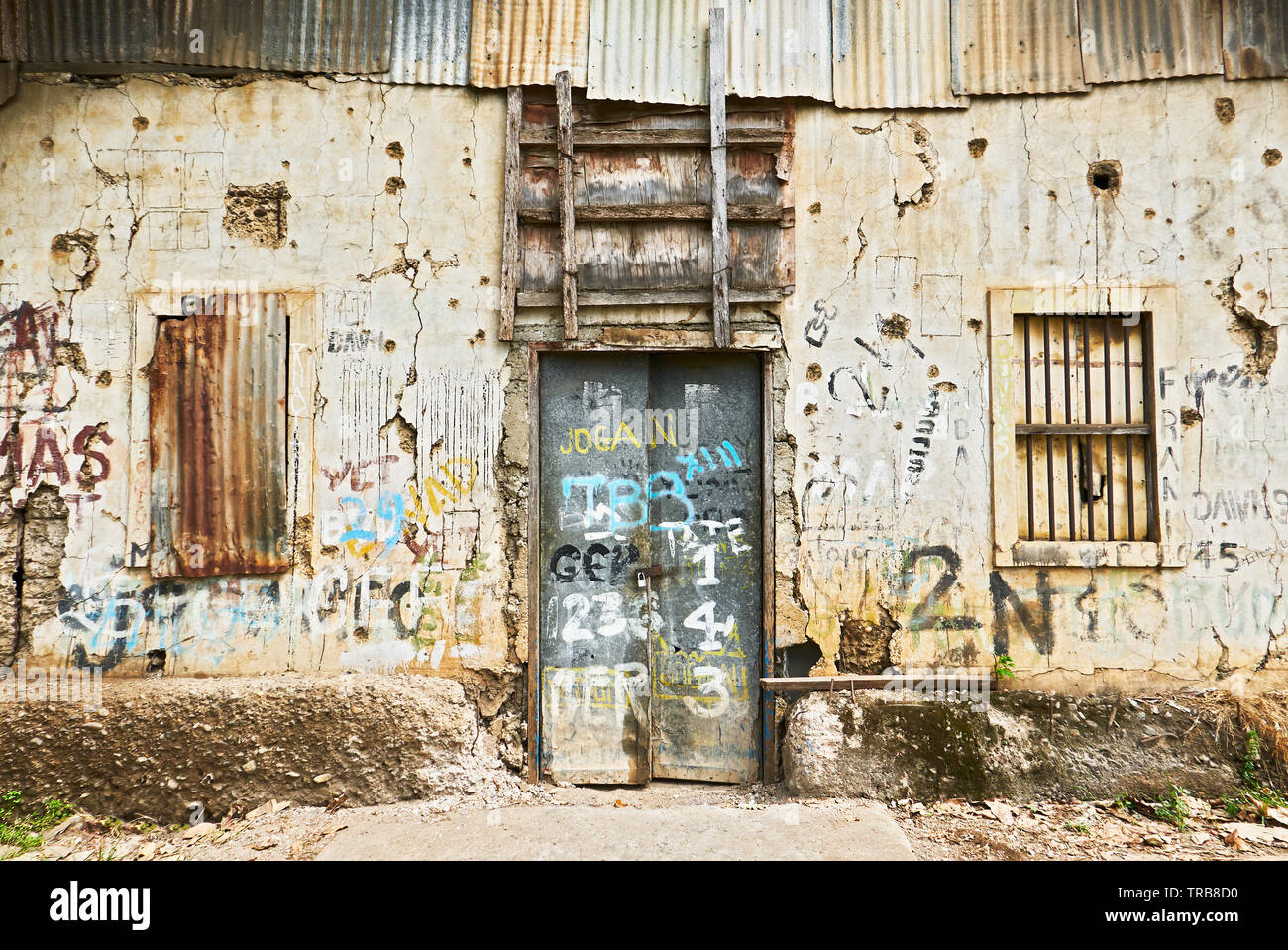 Puerto Princesa City, PALAWAN FILIPPINE: Vista ravvicinata del frontale di un abbandonato edificio rovinato con le finestre chiuse e la porta Foto Stock