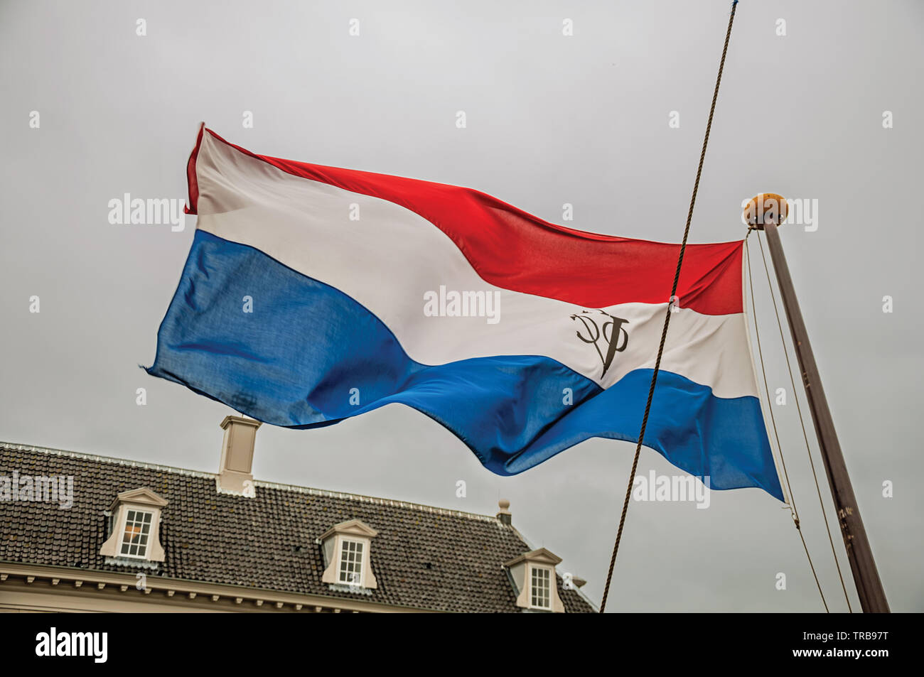 Colorato Dutch East India Company bandiera svolazzanti sul giorno nuvoloso in Amsterdam. Città con enorme attività culturali, dei canali e dei ponti nei Paesi Bassi. Foto Stock