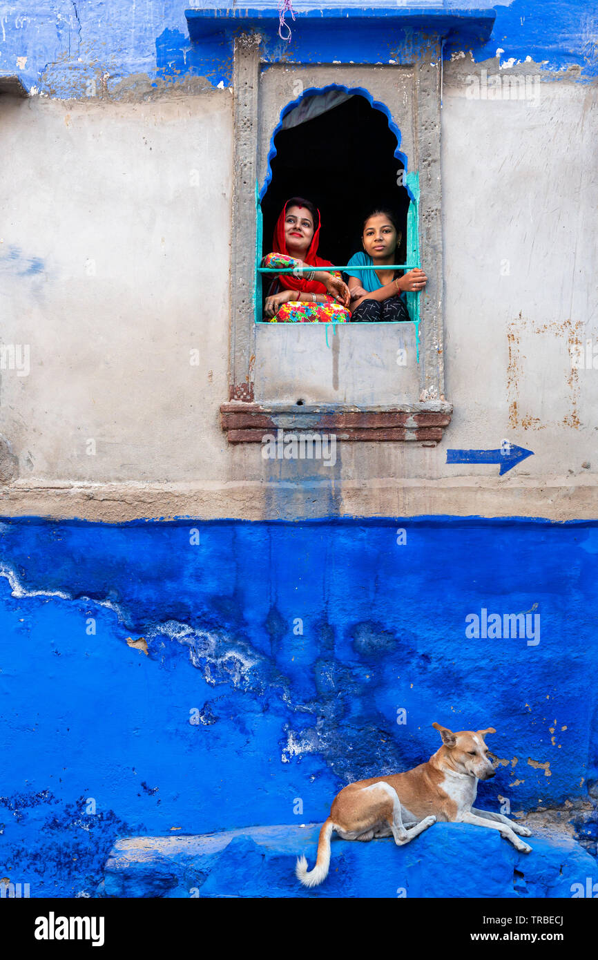 Due donne guardando fuori della finestra nella città blu di Jodhpur, Rajasthan, India Foto Stock
