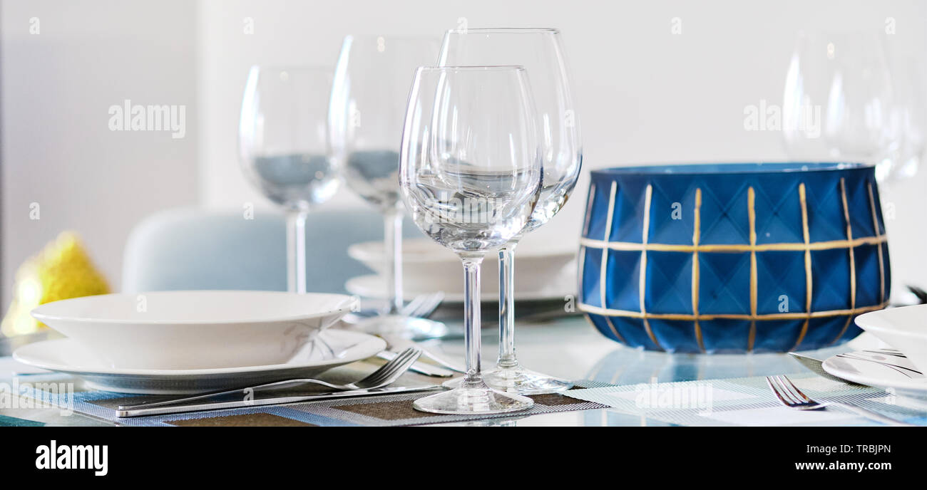 L'immagine orizzontale impostazione tabella vuota con bicchieri da vino bianco Ciotole Piatti e posate serviti al tavolo. Close up di stoviglie, piatti, nessuno Foto Stock