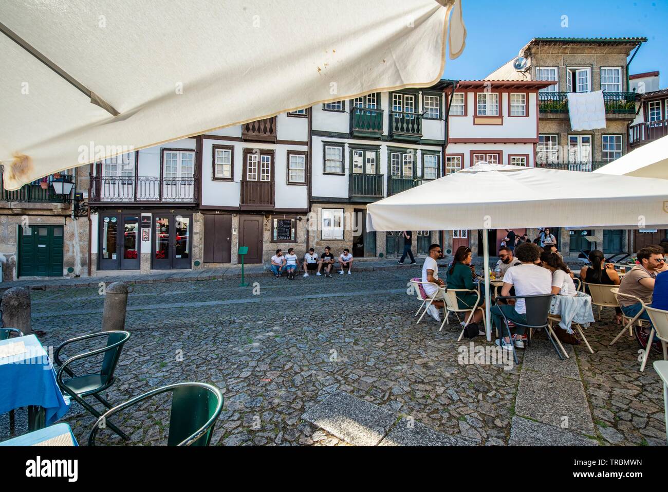 Guimaraes, Portogallo.turisti e abitanti rilassante sul marciapiede e nei ristoranti sulla bellissima Praca San Tiago Foto Stock