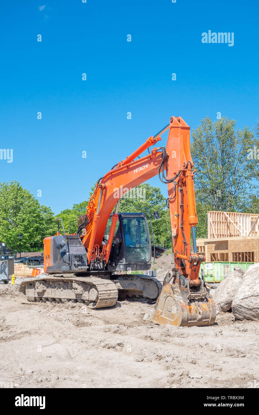 Escavatore siede presso il sito di nuova costruzione in casa in una suddivisione del progetto. Foto Stock