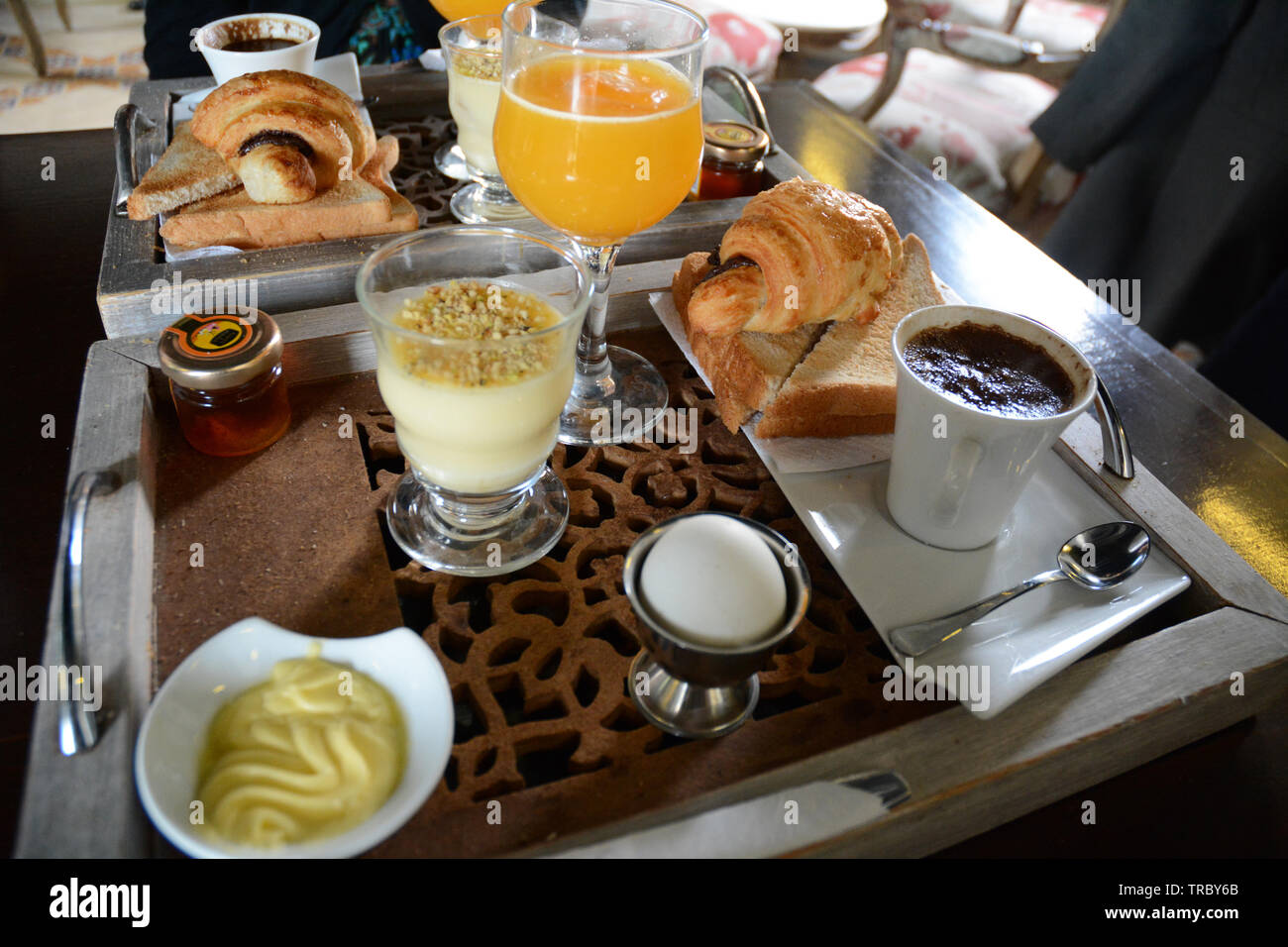 Continentale colazione tunisino di caffè, succo d'arancia, croissant, crema pasticcera, un uovo, toast, marmellata e burro a cafe nella medina di Tunisi, Tunisia. Foto Stock