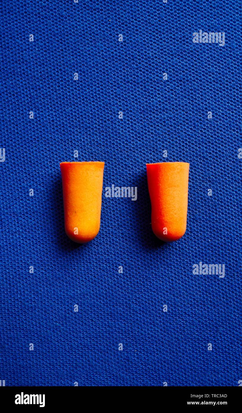 Orange i tappi per le orecchie isolato su blu Foto Stock