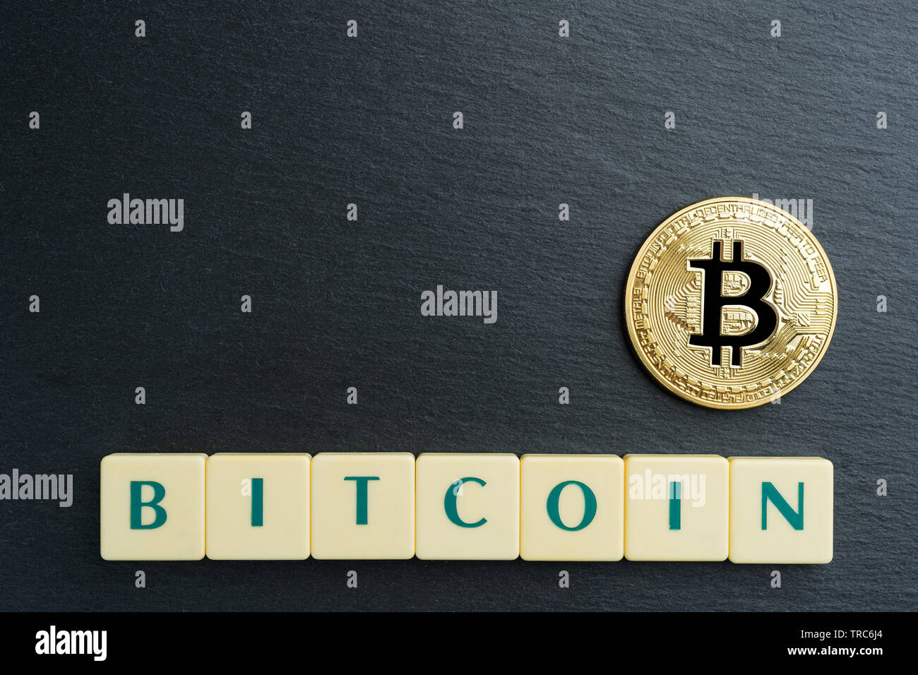 Bitcoin fisico moneta in oro con testo realizzati al di fuori della lettera di piastrelle. Cryptocurrency. Spazio di copia nell'angolo in alto a sinistra. Foto Stock