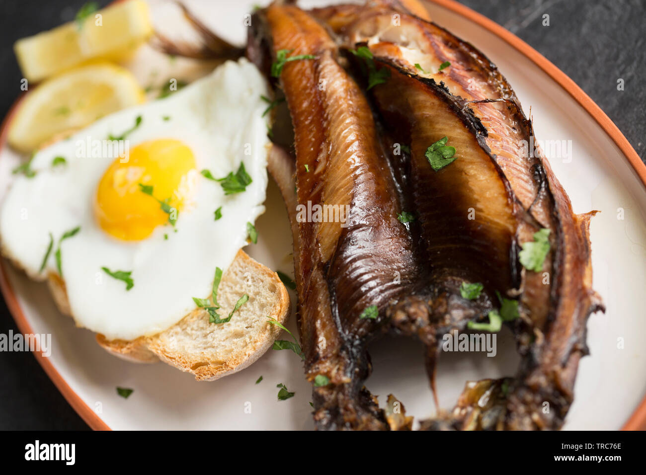 Un grigliato a freddo affumicato Kipper Craster realizzato da un oceano atlantico Aringa Clupea harengus, che ha servito per la prima colazione con una fetta di pane abbrustolito sourdo Foto Stock
