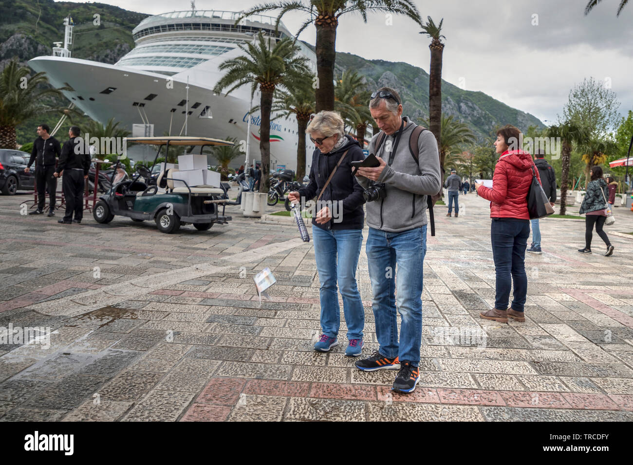 Kotor, Montenegro, 30 Aprile 2019: scene di strada con una turista perdendo in attesa del suo opuscolo a causa del colpo di vento Foto Stock