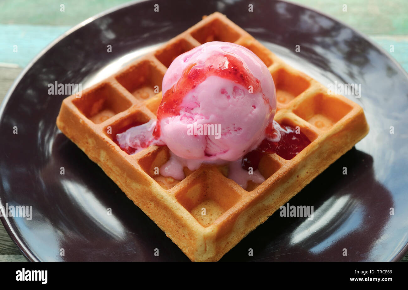 Freschi di forno Waffle guarnita con gelato alla fragola sul marrone scuro piastra Foto Stock