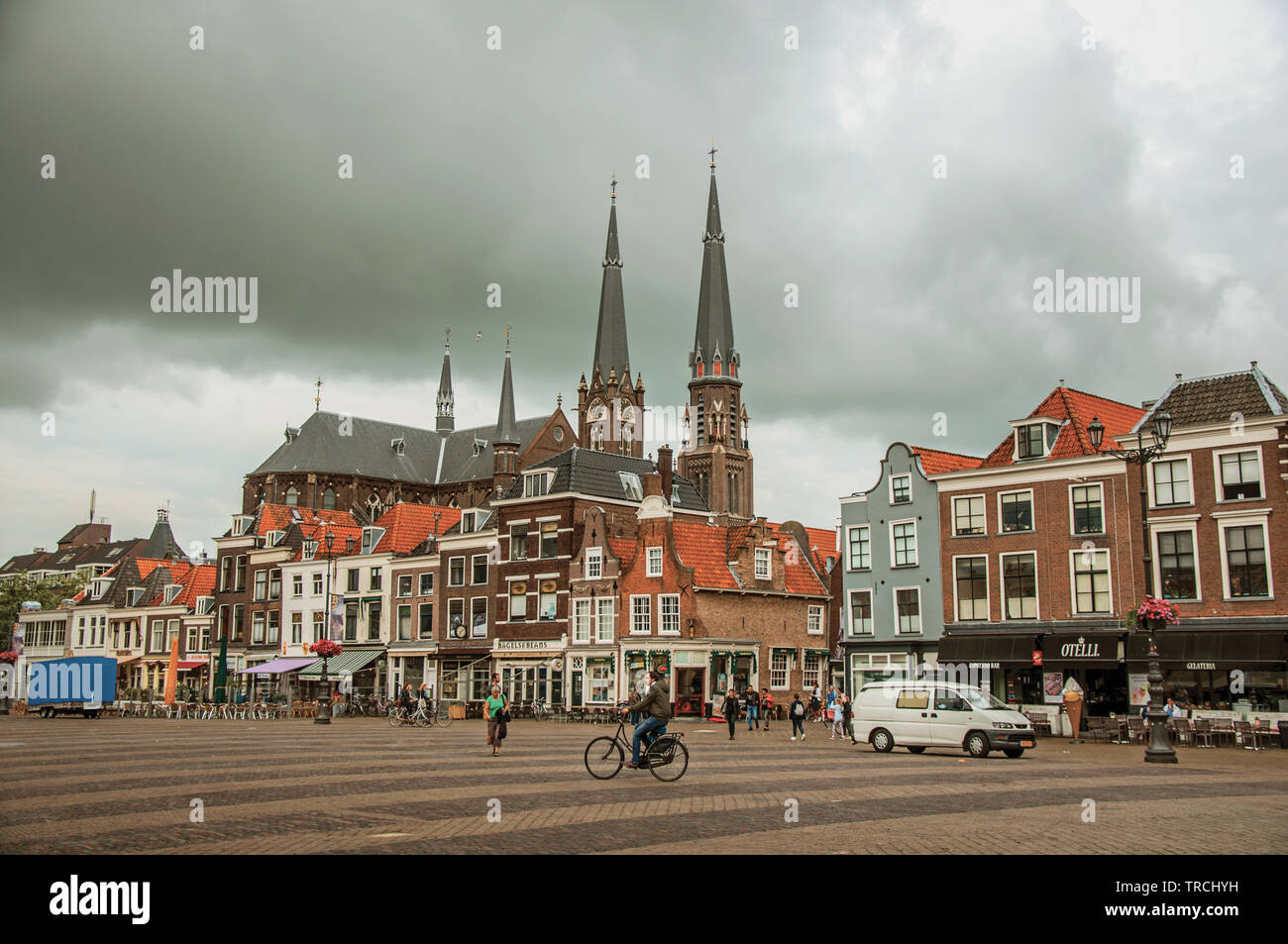 La gente sulla piazza del mercato, edifici in mattoni con negozi e steeple in Delft. Grazioso villaggio pieno di canali e di architettura gotica in Paesi Bassi. Foto Stock