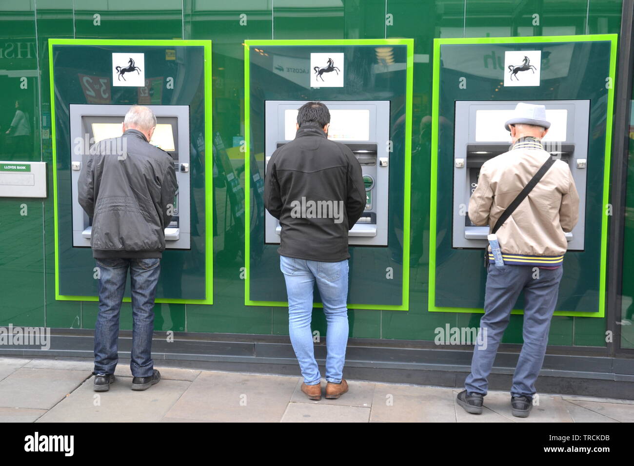 Tre Lloyds Bank atm essendo utilizzato da tre uomini su Market Street, Manchester, Regno Unito Foto Stock