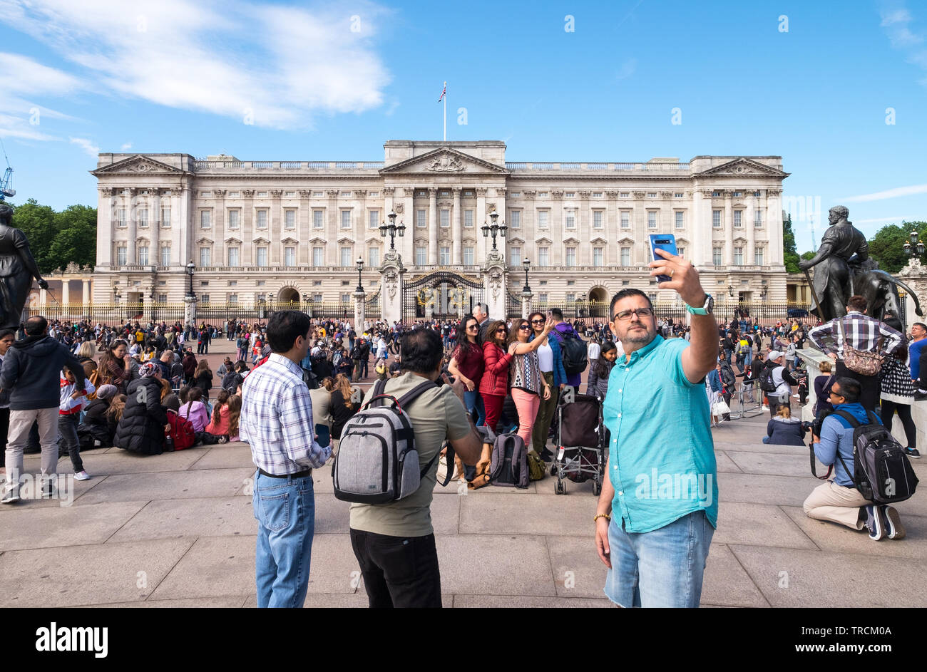 I turisti tenendo selfies e fotografie fuori Buckingham Palace, London, England, Regno Unito Foto Stock