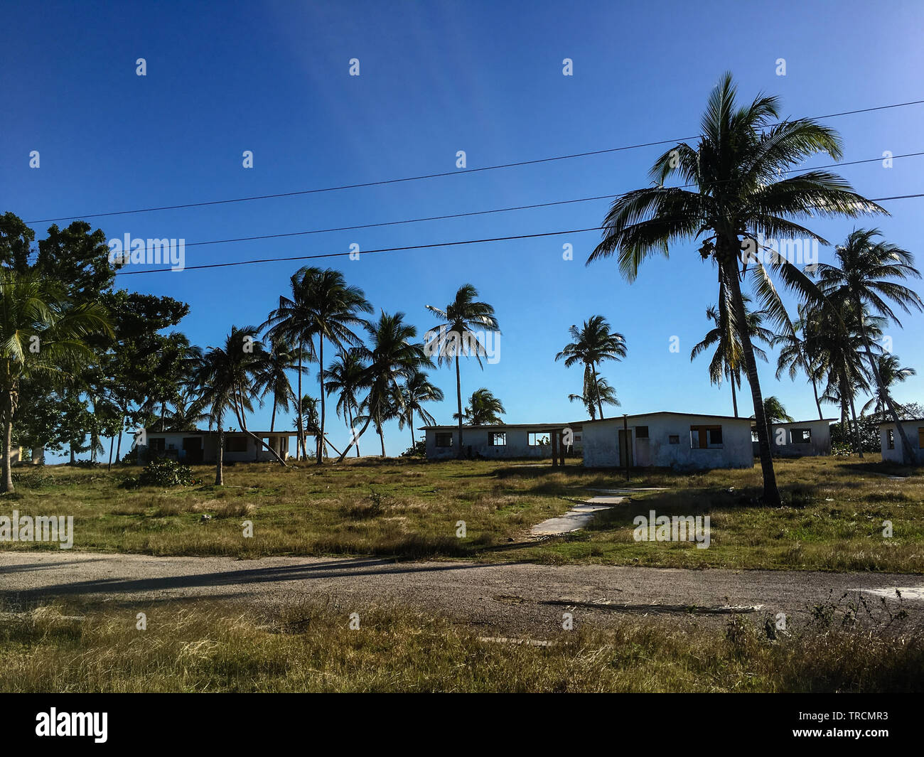 Sole oltre il abbandonate case vacanza e palme vicino a Playa Coco in Playa Giron, Cuba Foto Stock