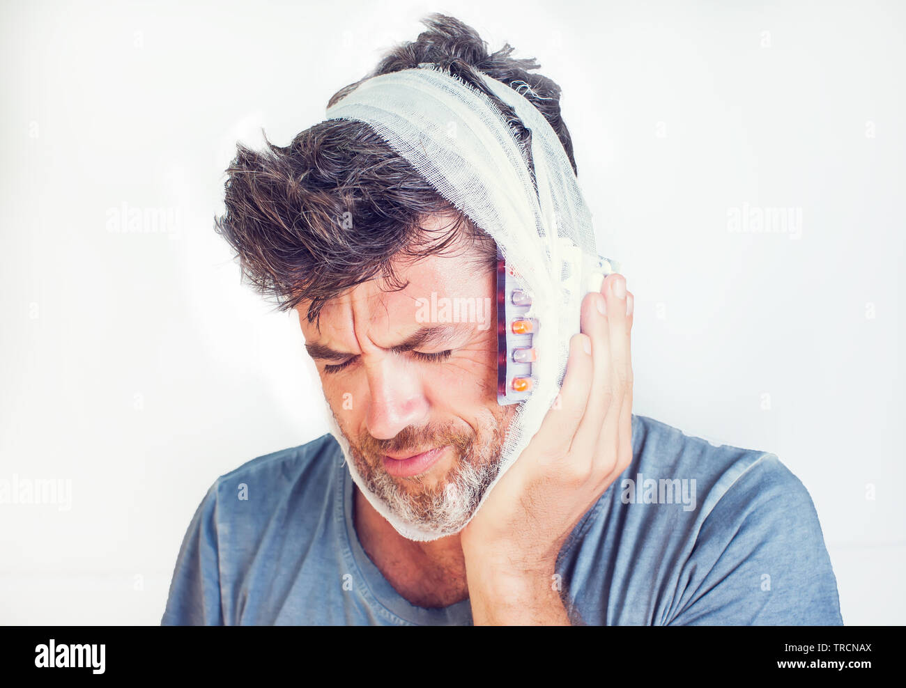 Uomo in medical bendaggio e pillole isolato su sfondo grigio Foto Stock