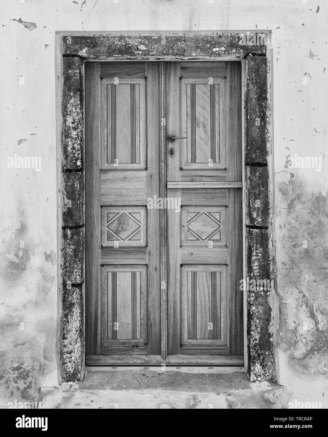 Bloccata la porta di legno circondato da un involucro fatto di rocce laviche in Oia - Santorini. Foto Stock