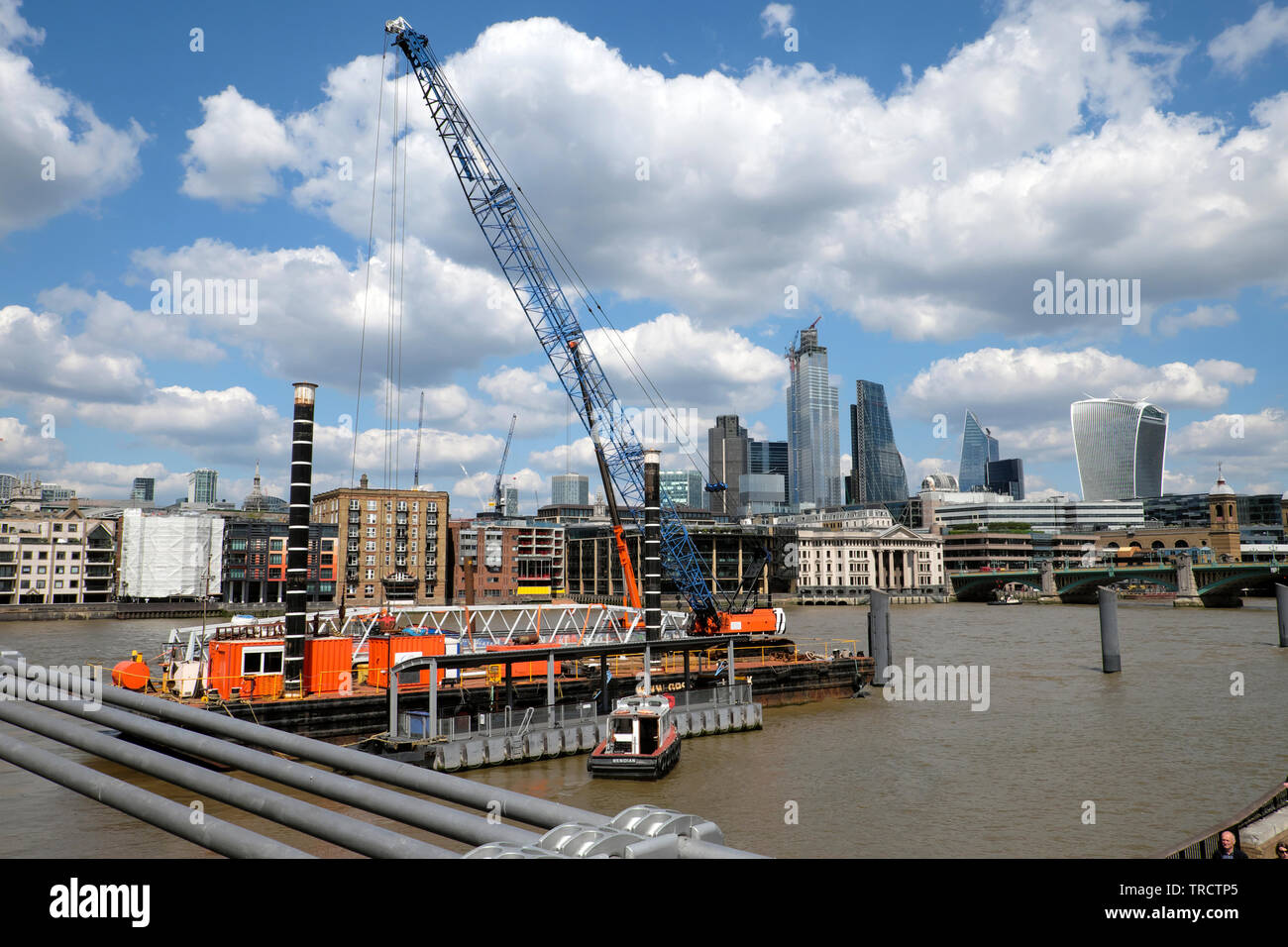 La gente che lavora e gru su chiatta sul Fiume Tamigi visto dal Millennium Bridge verso la città di grattacieli di Londra UK 2019 KATHY DEWITT Foto Stock