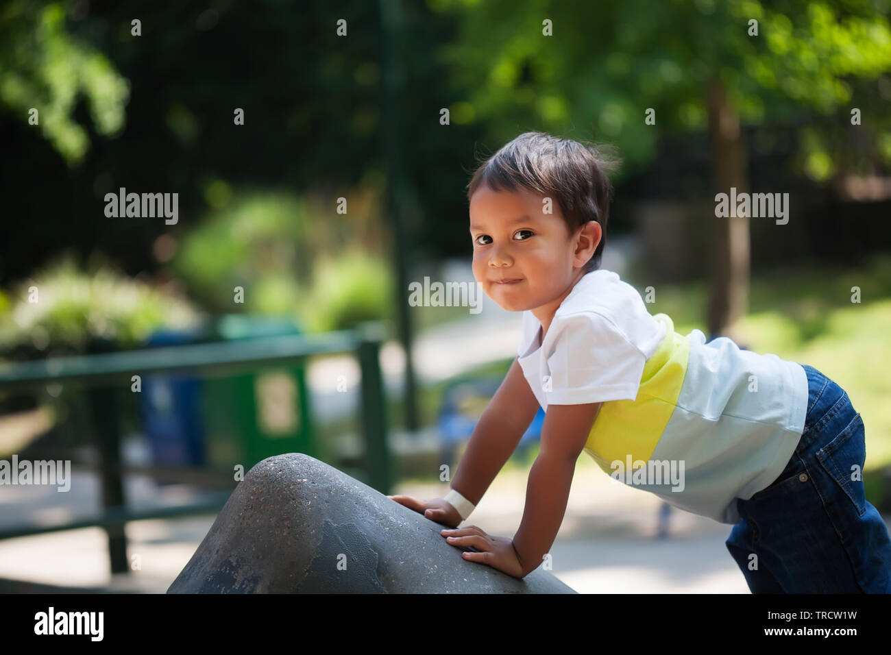 Giovane ragazzo qualcosa di arrampicata in un parco giochi per bambini parcheggio durante il tramonto, il supporto di se stesso con le sue mani e braccia. Foto Stock