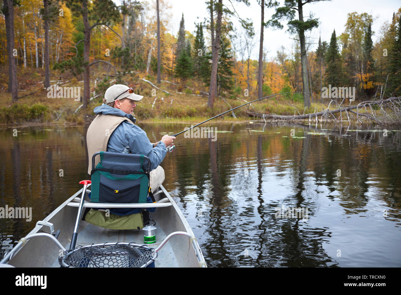 40s pescatore caucasica la pesca da una canoa sul piccolo lago nel nord del Minnesota durante la caduta Foto Stock