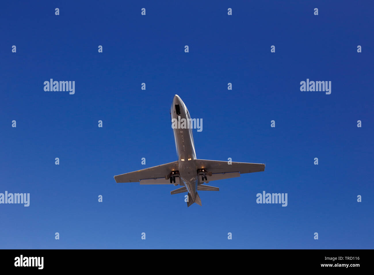 Basso angolo vista di grigio di un jet di affari con distribuito di atterraggio contro un blu cielo chiaro. Foto Stock