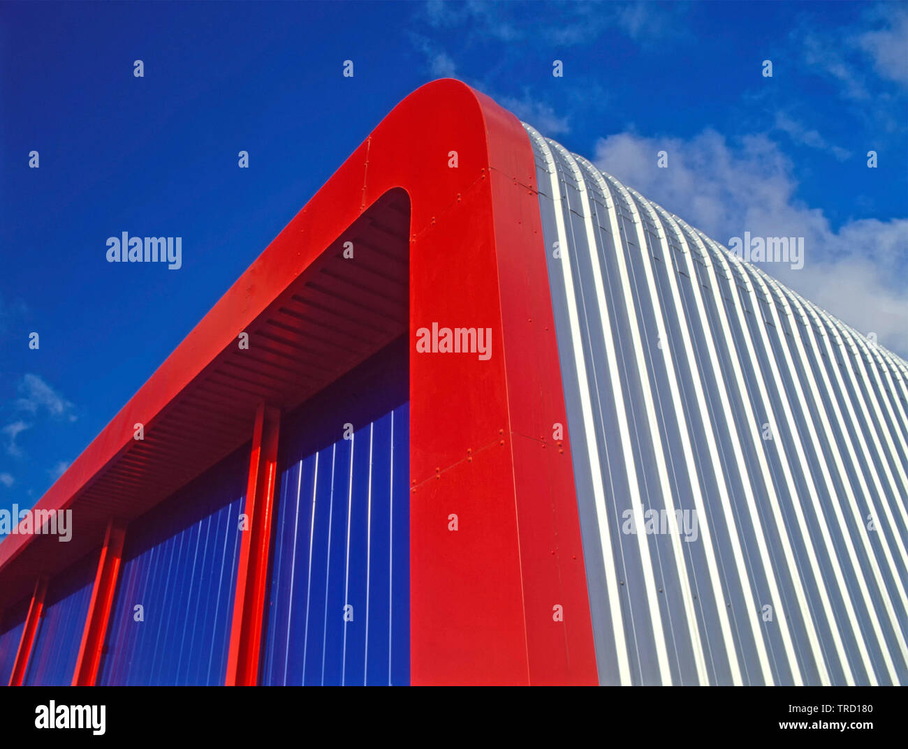 Rosso in acciaio telaio curvo ad angolo commerciale industriale magazzino edificio con forma arrotondata di colore argento laterale del tetto e dei pannelli di rivestimento England Regno Unito Foto Stock