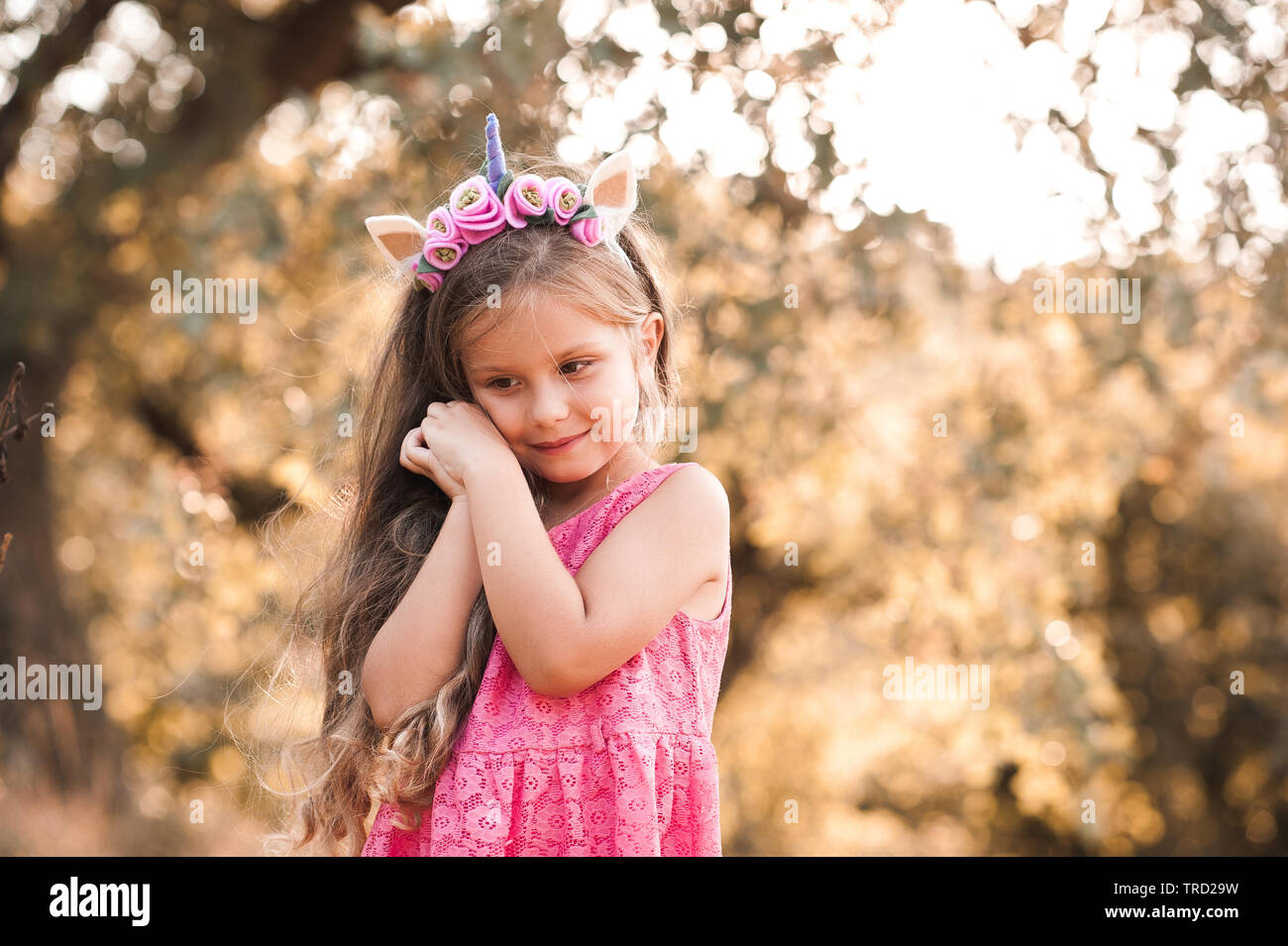 Sorridente bambina 4-5 anno indossando unicorn cerchietto per capelli e  abito rosa all'esterno. Infanzia Foto stock - Alamy