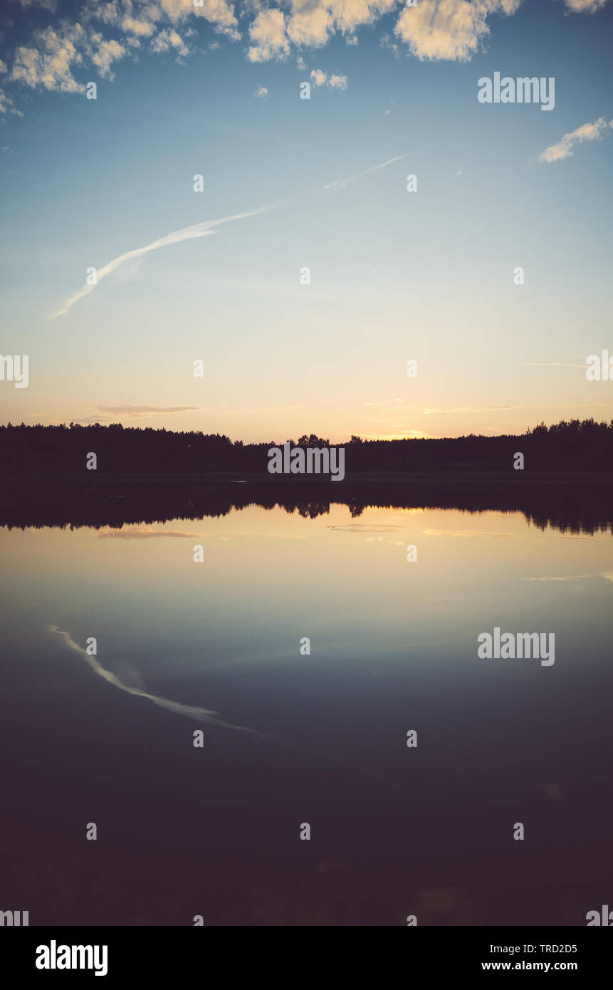 Scenic tramonto riflesso in un lago calmo, tonificazione del colore applicato, sfondo naturale. Foto Stock