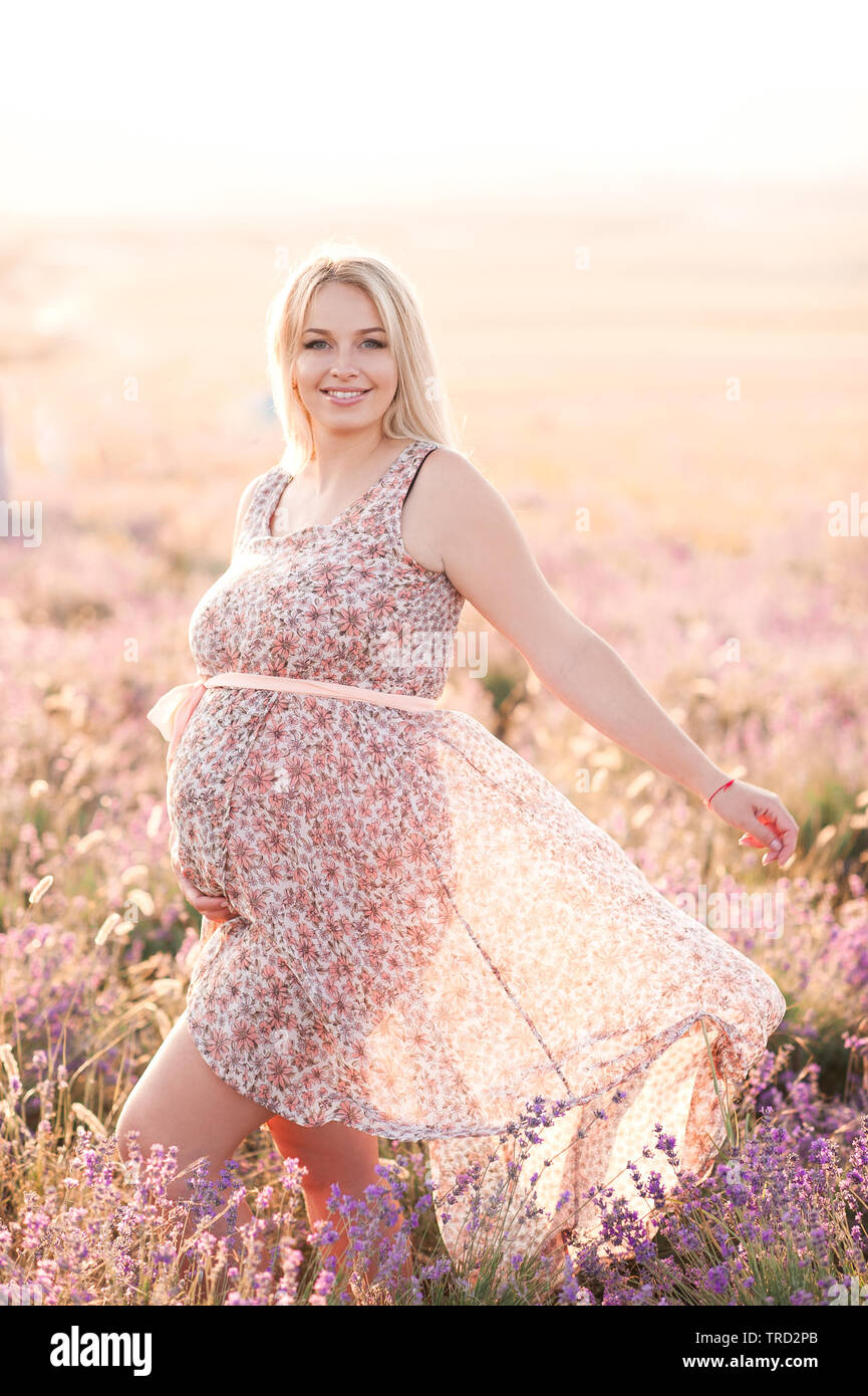 Sorridente donna incinta indossando abiti eleganti con motivo floreale in  prato. Guardando alla fotocamera. La maternità. La maternità Foto stock -  Alamy
