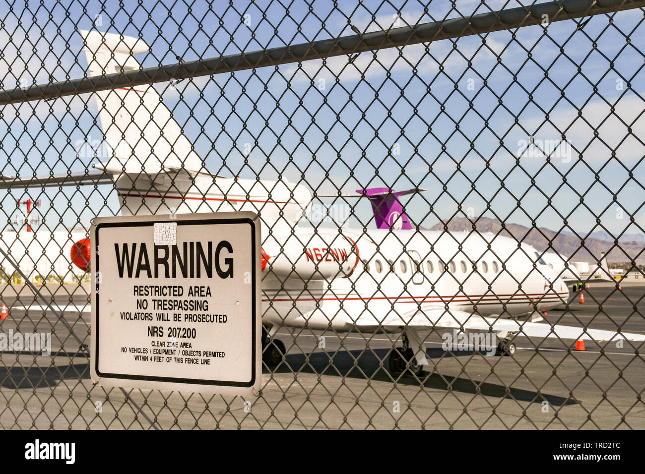 LAS VEGAS, NEVADA, STATI UNITI D'AMERICA - Febbraio 2019: Segno di avvertimento in un recinto presso l'Aeroporto Internazionale McCarran. In fondo è un Dassault Falcon jet 900 Foto Stock