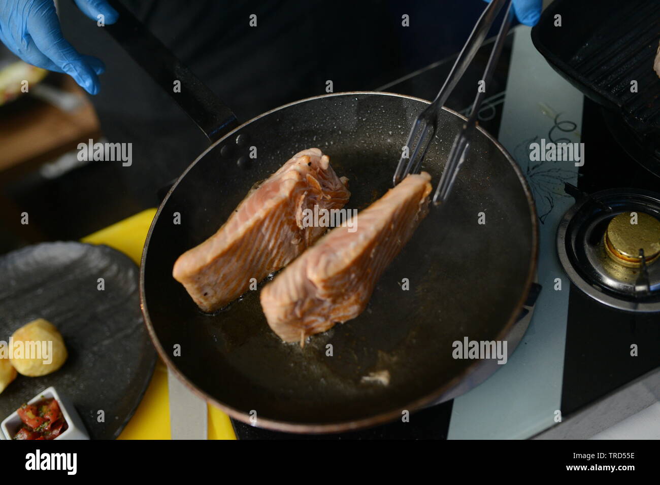 Il cuoco cuoce pesce nel ristorante Foto Stock