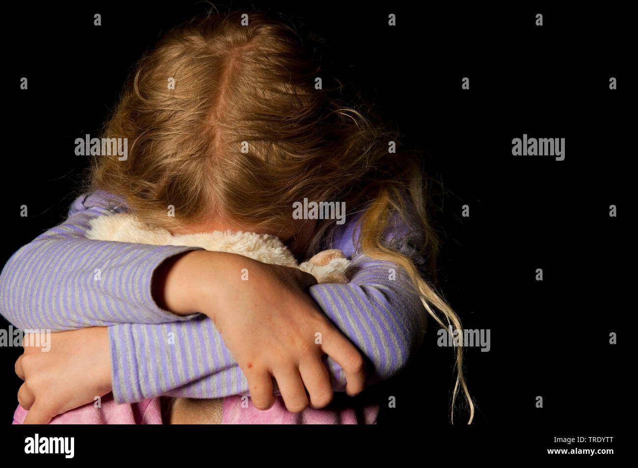 Ritratto di una giovane ragazza, hidding la testa dietro un peluche - abuso di minori Foto Stock