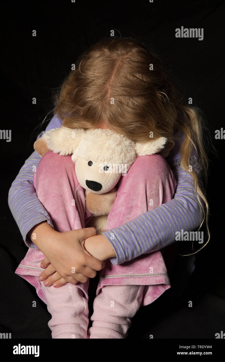 Ritratto di una giovane ragazza, hidding la testa dietro un peluche - abuso di minori Foto Stock