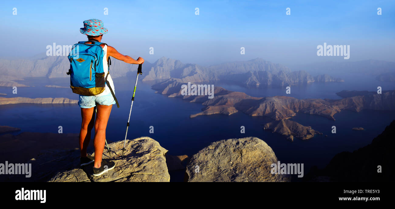 Femmina wanderer godendo la vista da una montagna alta alla Baia di Sham, Oman, Khasab Foto Stock