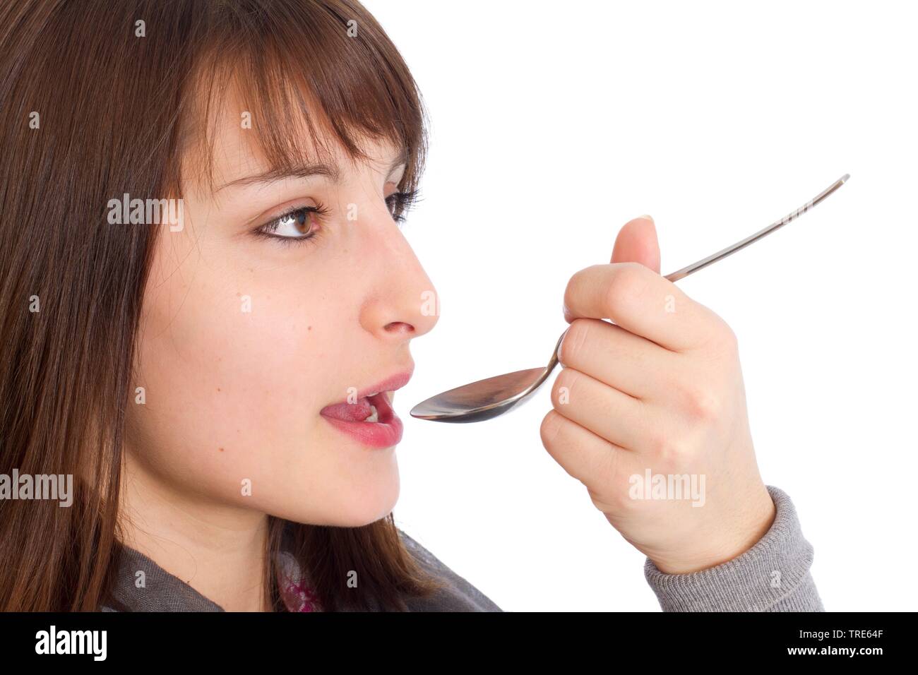 Vista laterale di una giovane donna di prendere la medicina a freddo da un cucchiaio Foto Stock