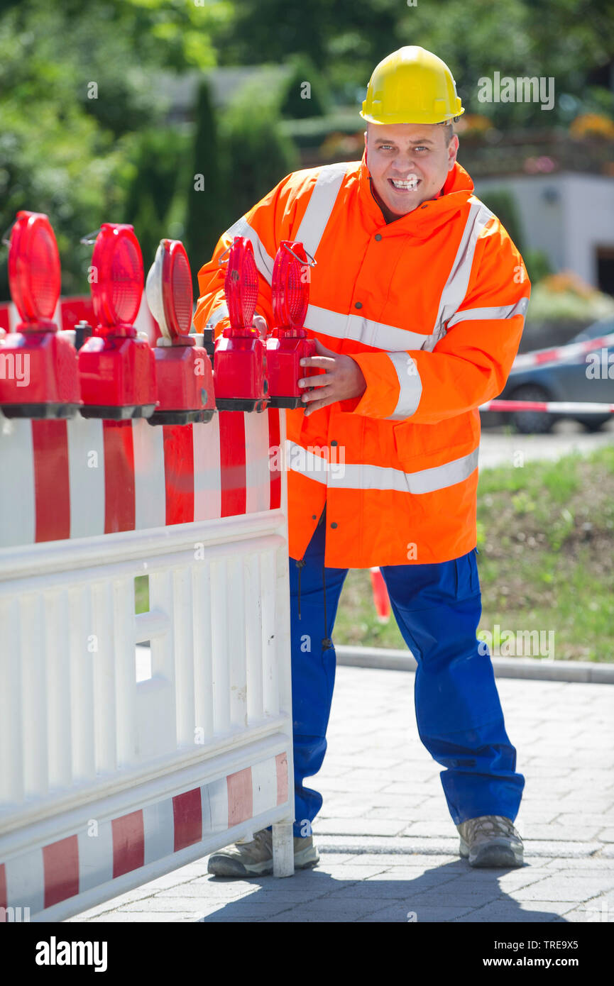 Operaio edile in un arancio ad alta visibilità giacca, installando una diga Foto Stock