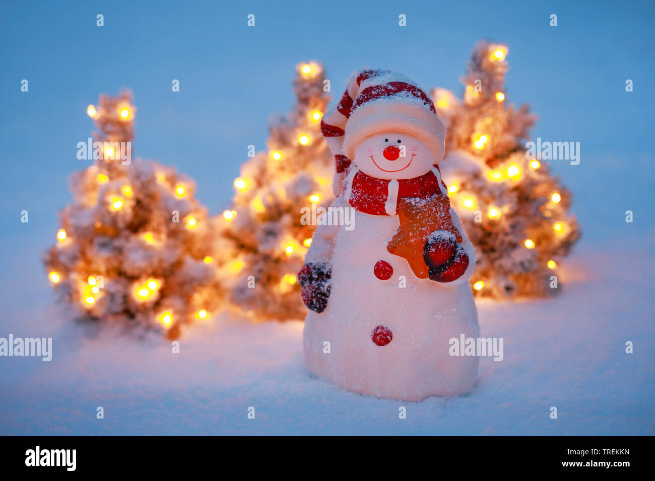Pupazzo di neve e illuminato piccoli alberi di Natale nella neve Foto Stock