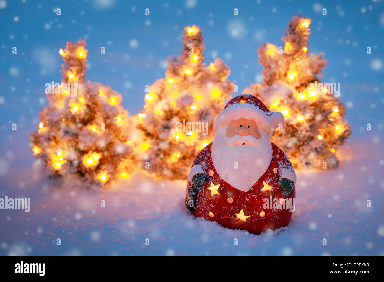 Babbo Natale e la piccola illuminata di alberi di Natale nella neve Foto Stock