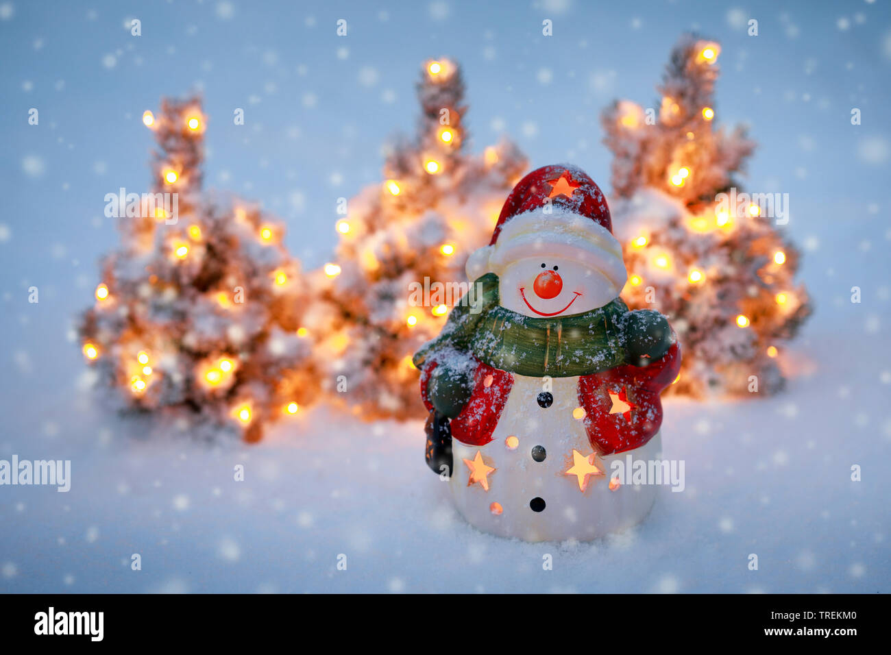 Pupazzo di neve e illuminato piccoli alberi di Natale nella neve Foto Stock