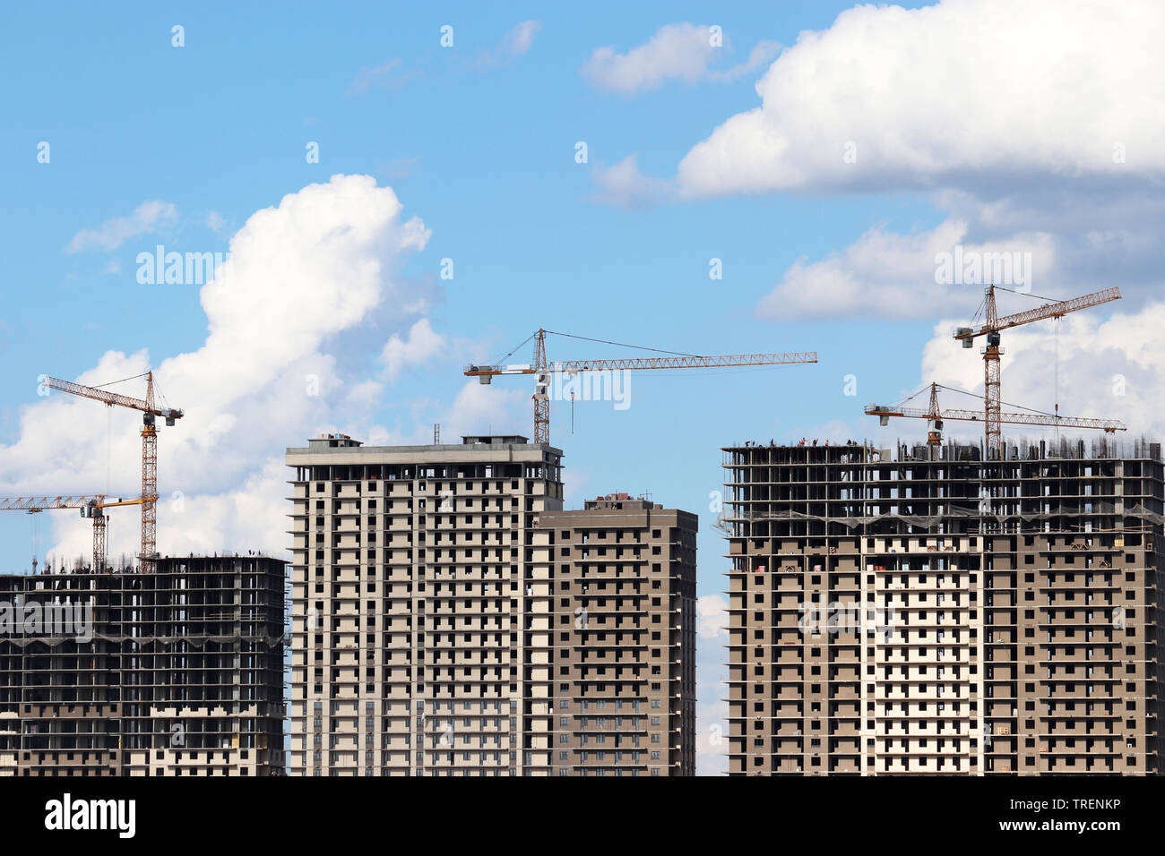 Costruzione di gru e di alto-aumento edifici residenziali in costruzione sullo sfondo del cielo blu con nuvole bianche Foto Stock