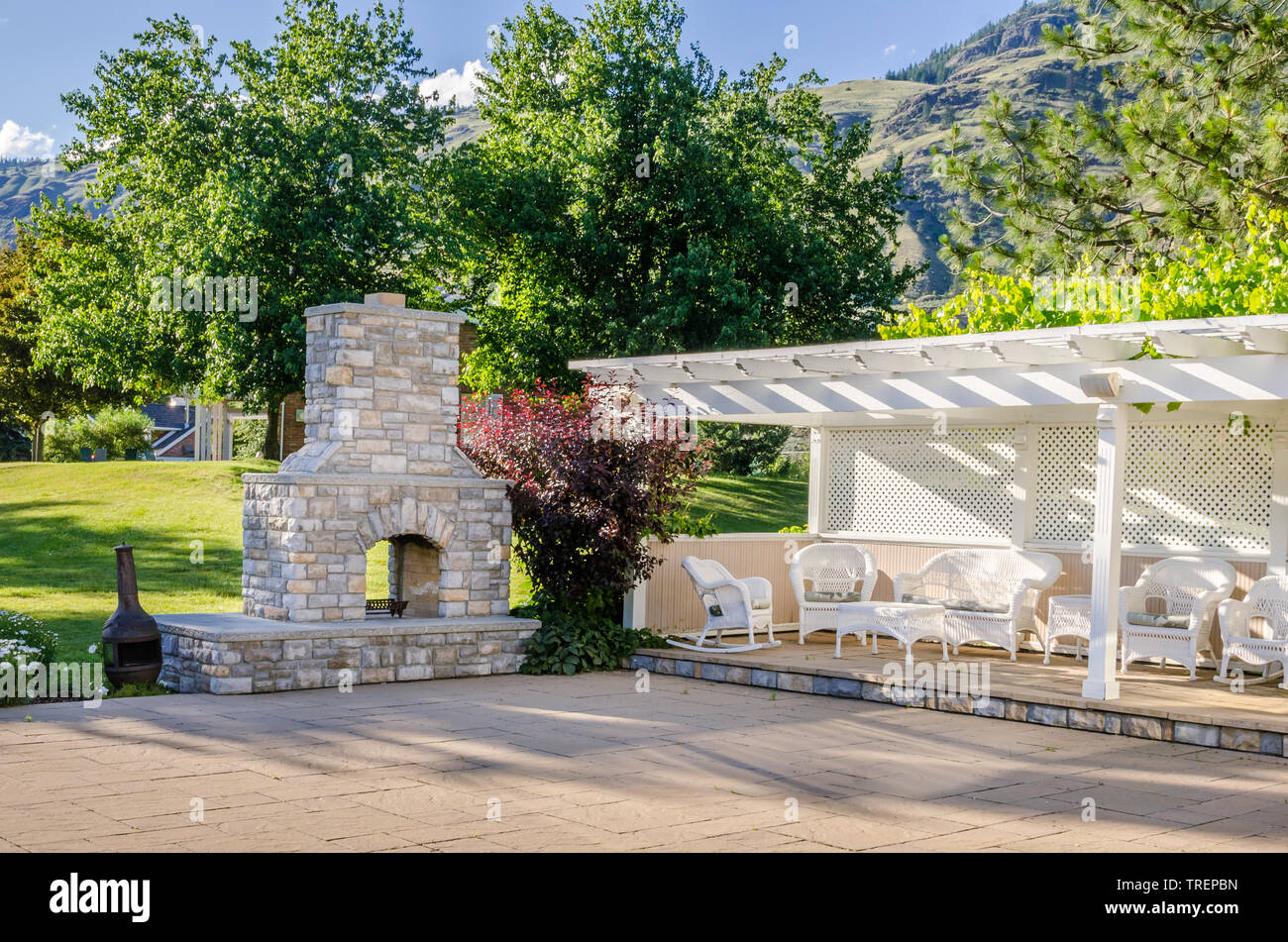 Backyard patio bianco con mobili da giardino e caminetto in pietra Foto Stock