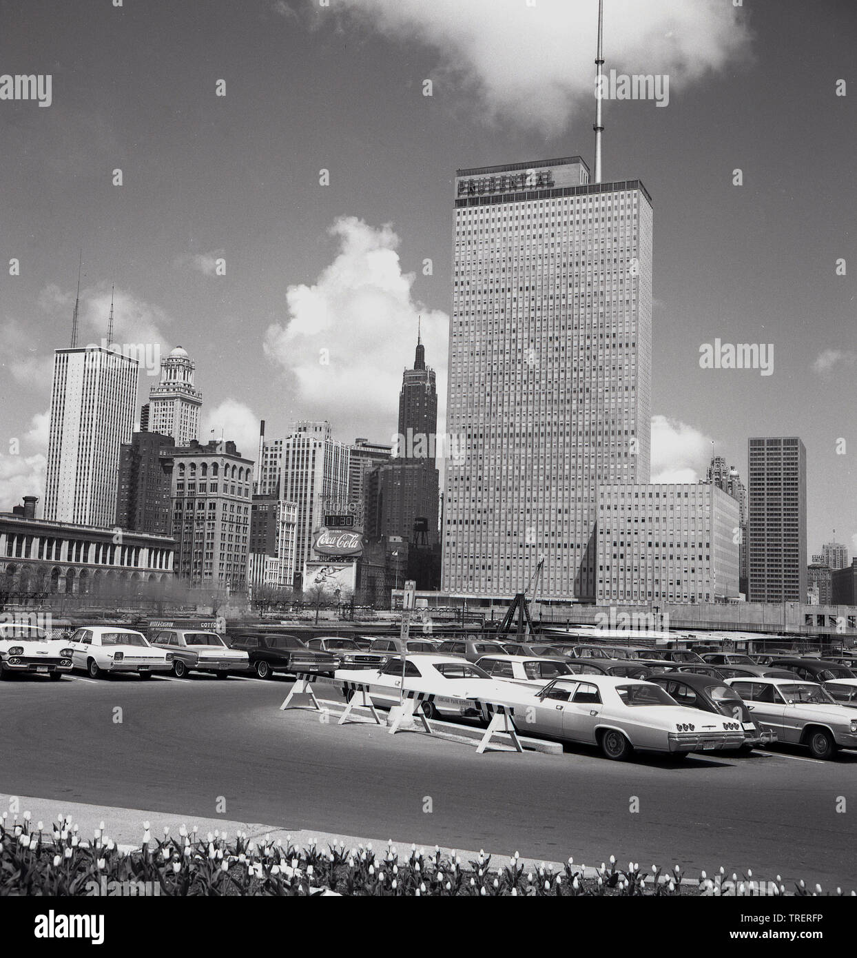 1960s, storico, Chicago, e attraverso un parcheggio di automobili americane, una vista della città che mostra i grattacieli e blocchi di uffici, uno è quello della compagnia di assicurazione americana, Prudential. Foto Stock