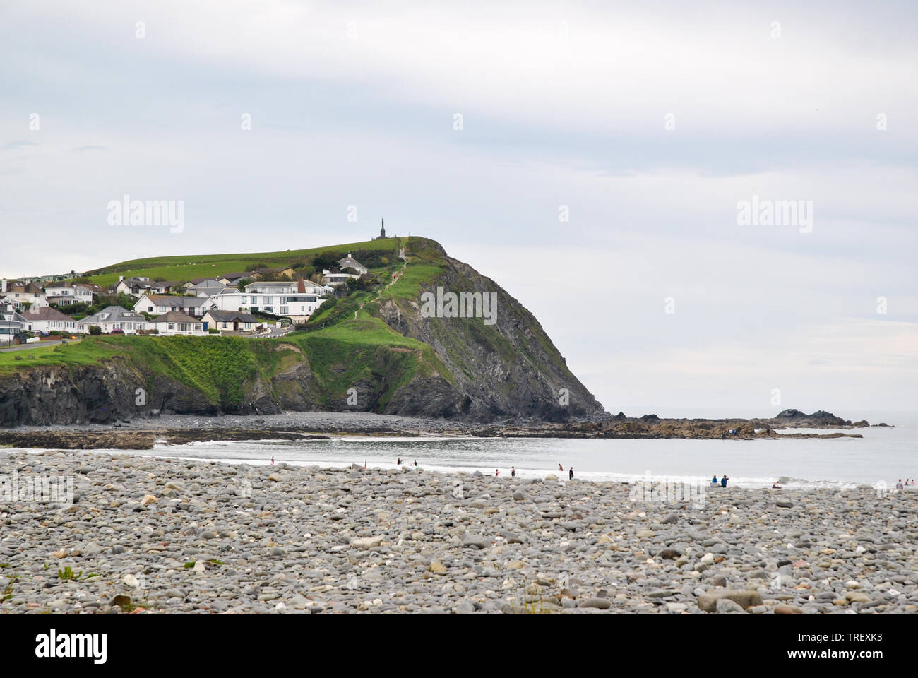 Un primo piano vista della spiaggia e scogliere in sfondo mostrante Borth Memoriale di guerra sulla cima più alta Foto Stock