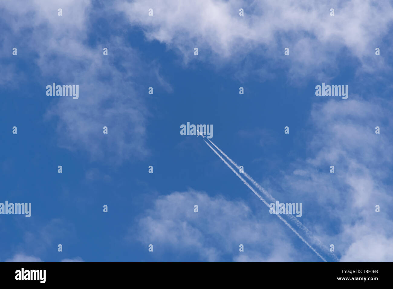 Un aereo jet vola attraverso le nuvole wispy su una summer blue sky giorno Foto Stock
