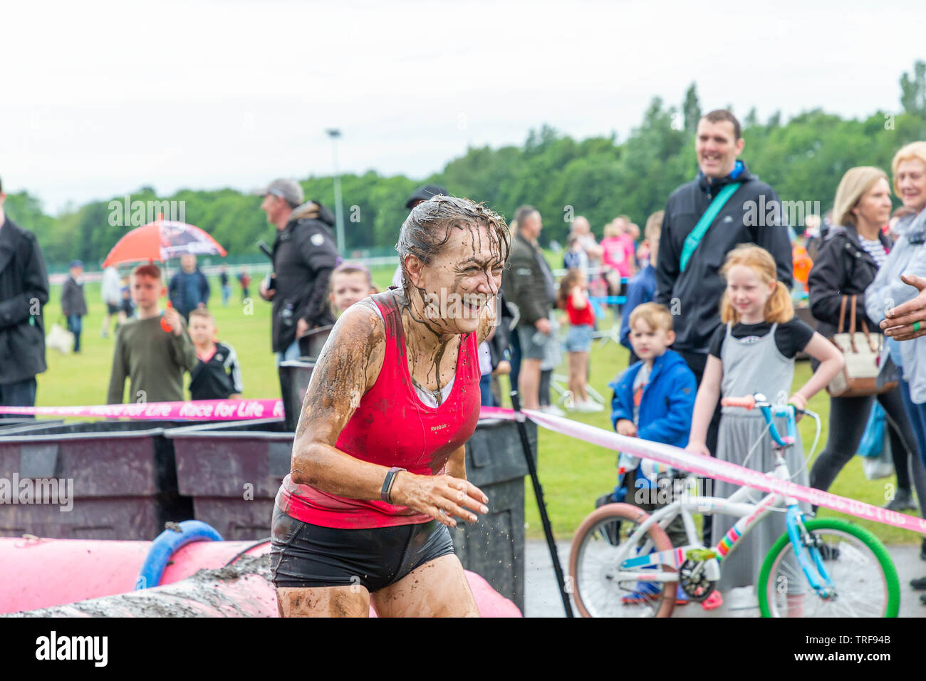 Warrington, Regno Unito. 2 Giugno 2019. Gara per la Vita 2019, Warrington, in aiuto della ricerca sul cancro. I corridori arrivare imbevuto di acqua fangosa al pozzo del fango Foto Stock