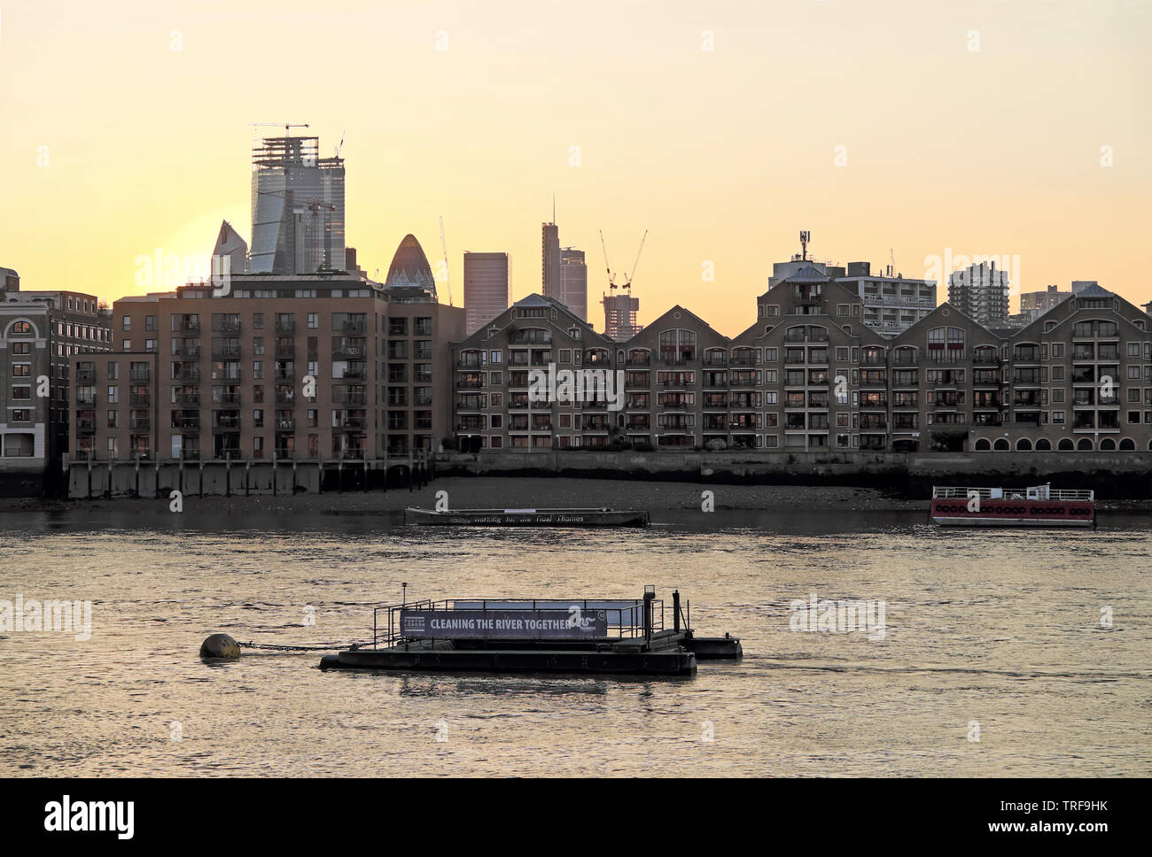 Pontone chiatta galleggiante nel fiume Tamigi con il segno "Pulizia del fiume insieme' vista di Wapping Riverside Apartments & City of London REGNO UNITO KATHY DEWITT Foto Stock