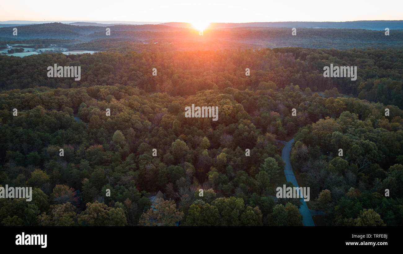 Scenic Sunrise la mattina presto vista aerea Fotografia Drone guardando in giù a Tree Tops tortuosa strada splendida alba sulle montagne colline in Orizzonte Foto Stock