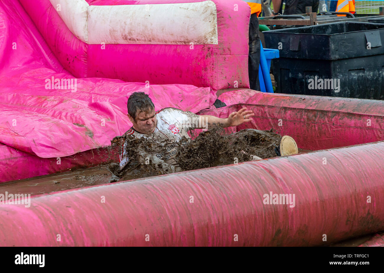 Warrington, Regno Unito. 2 Giugno 2019. Gara per la Vita 2019, Warrington, in aiuto della ricerca sul cancro. L'uomo tiene il suo respiro come egli scivola nel pozzo del fango Foto Stock